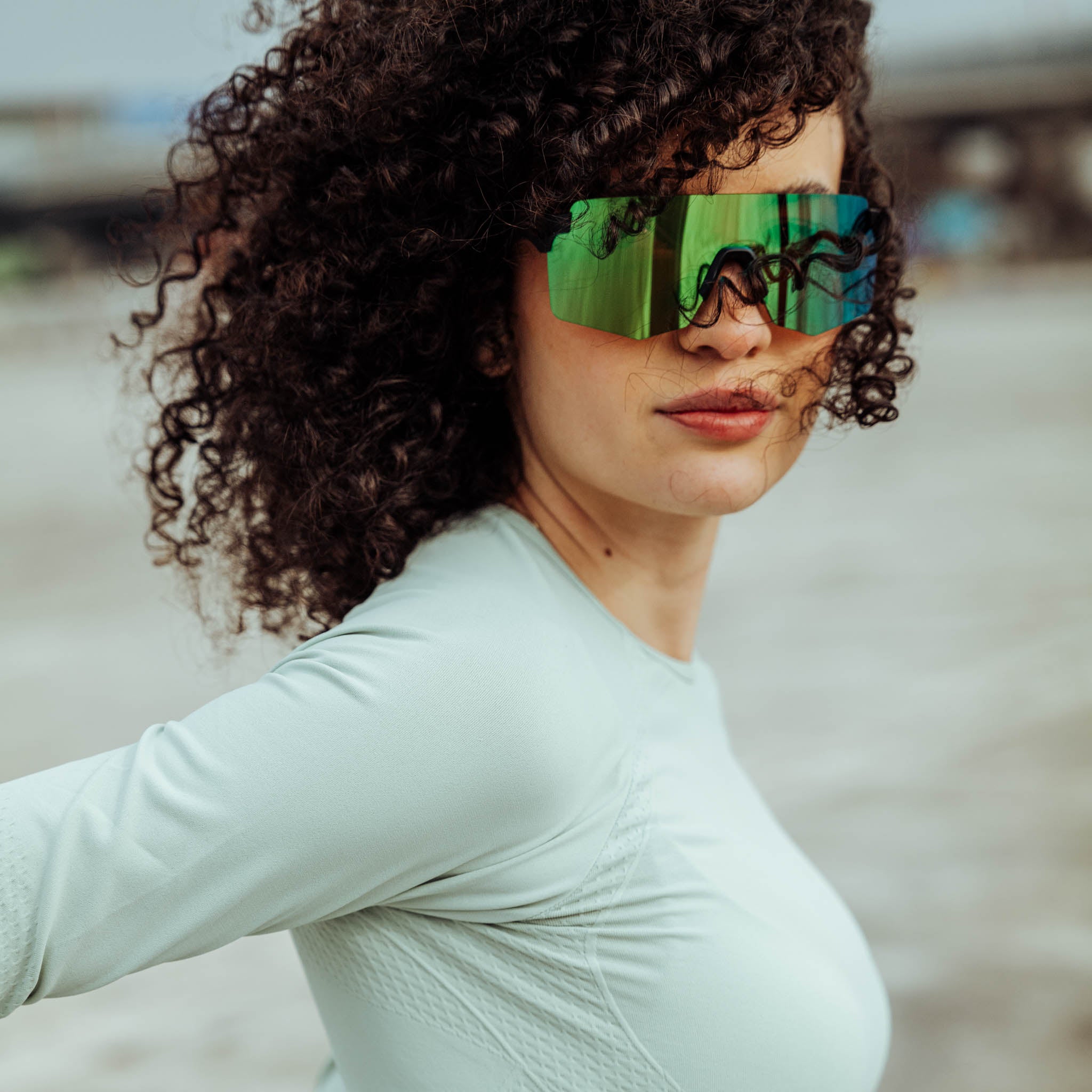 Junge Athletin mit lockigem Haar und großen grünen Sportsonnenbrille