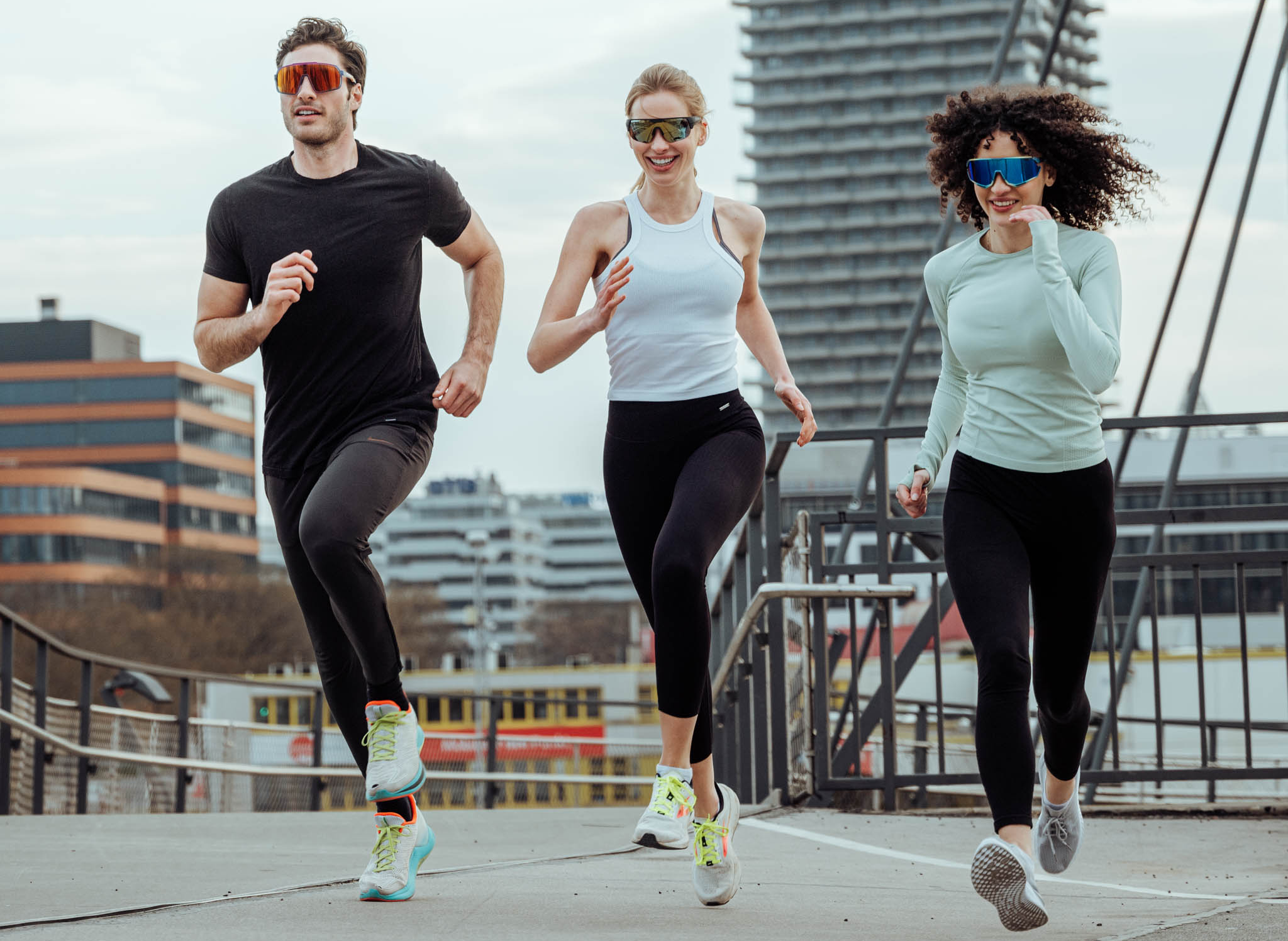 Athleten laufen gemeinsam in urbaner Umgebung, ausgestattet mit Laufbrillen
