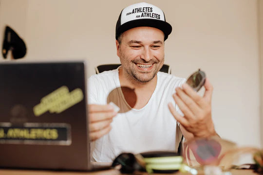 Mike Kofler, the face behind Athletes Eyewear, enthusiastically inspects sports glasses at his desk
