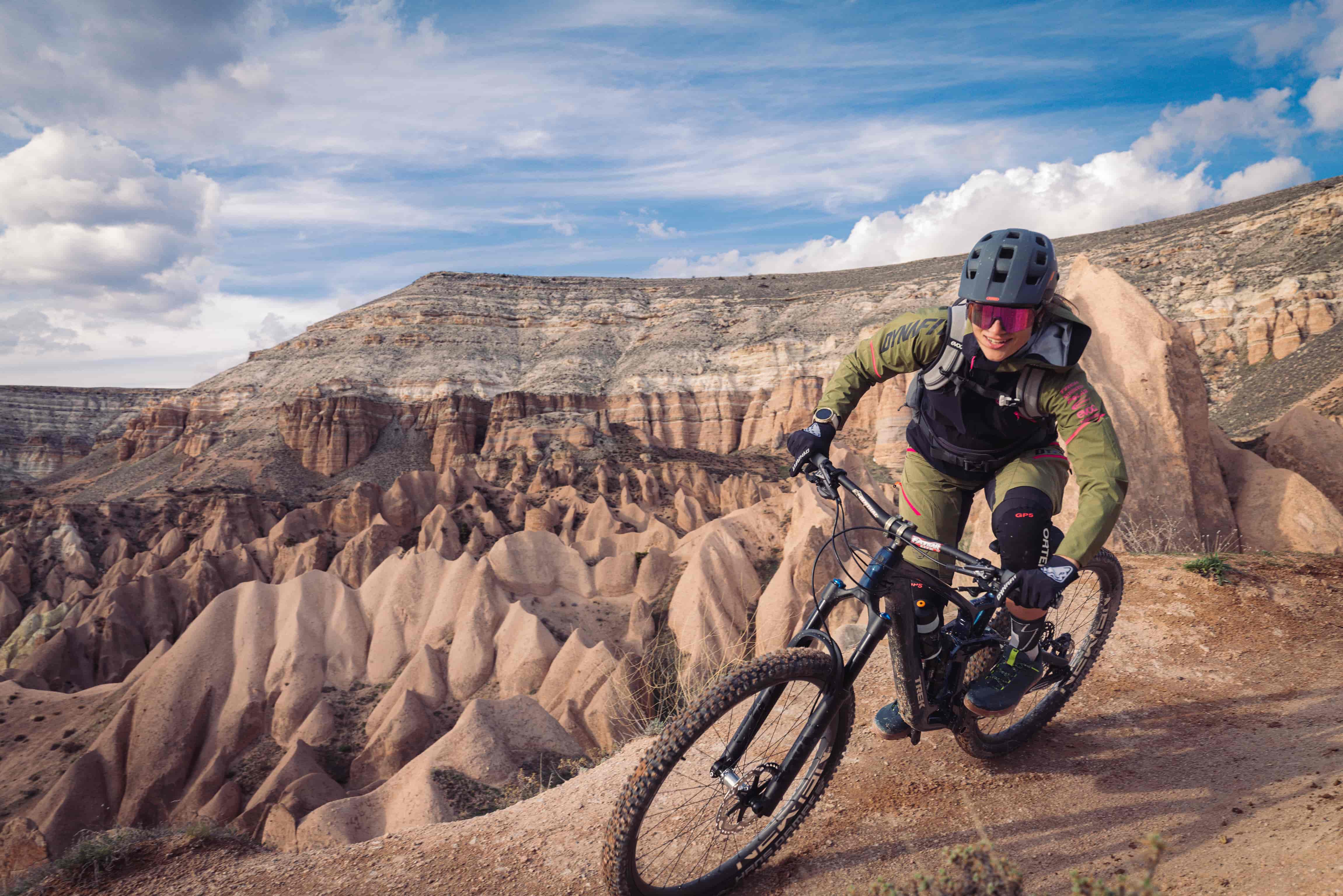 Mountain biker with helmet and sunglasses rides through rocky landscape