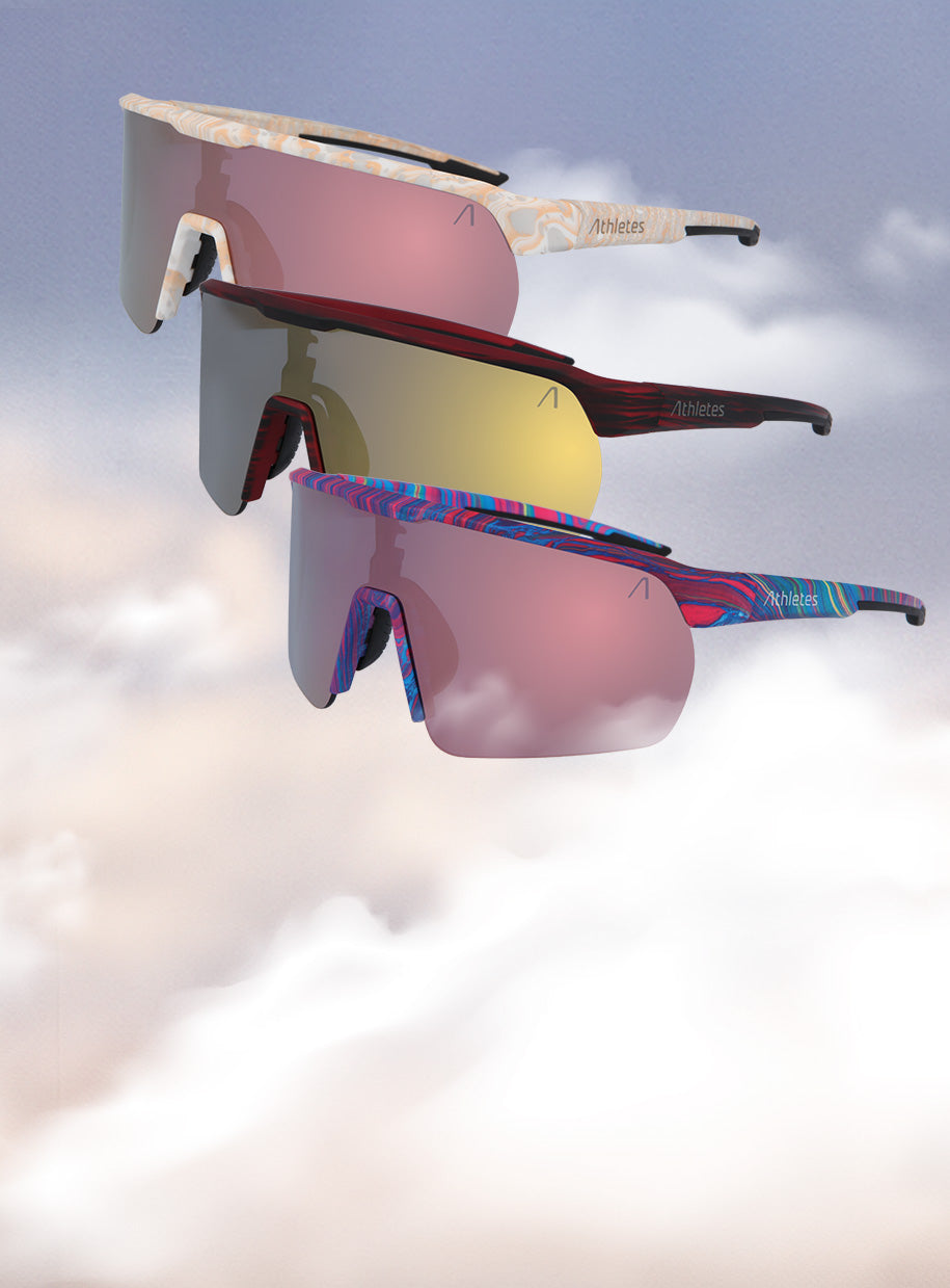 Drei Sportsonnenbrillen von Athletes Eyewear schweben vor einem Himmel mit Wolken