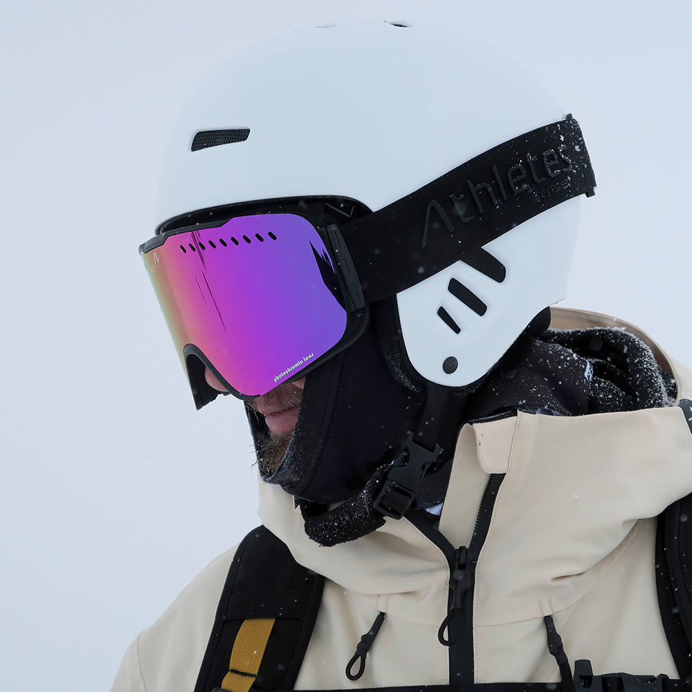 Mann mit Skihelm und reflektierender Skibrille in verschneiter Umgebung